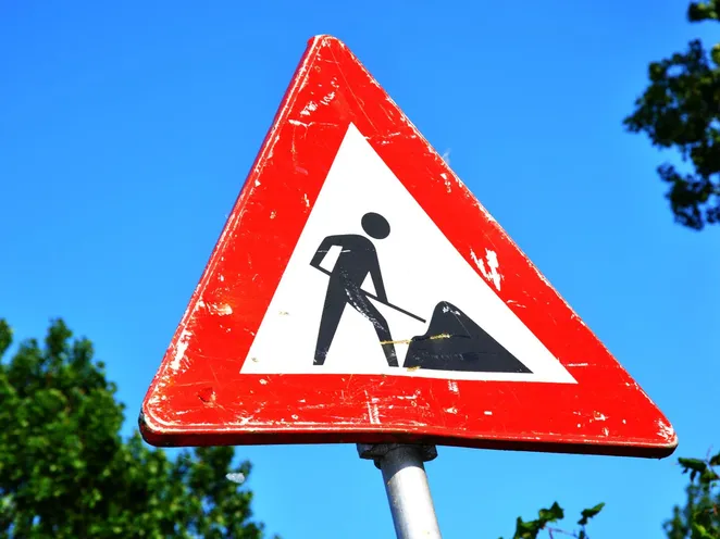 A red and white roadwork warning sign with a