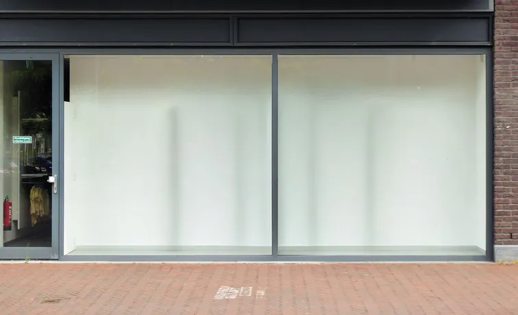 Empty high street retail unit with large glass windows and whitewashed interior