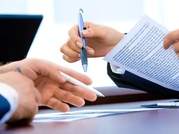 Two people reviewing a printed document at a desk
