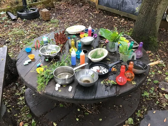 Pans, bowls and potion bottles set out on the mud kitchen table
