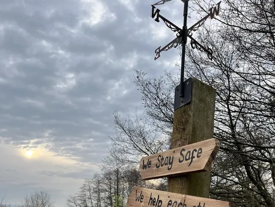 A wooden signpost reading we stay safe, we help each other, we respect nature, we take care of our forest school
