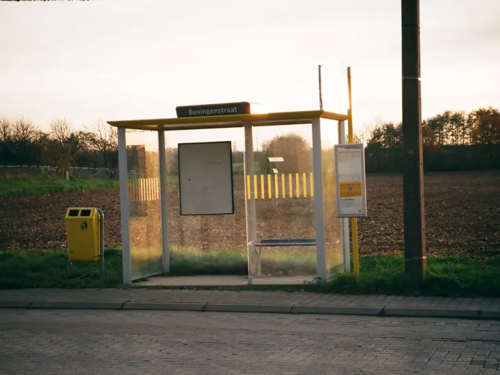 An empty bus shelter on a country roadside at sunset