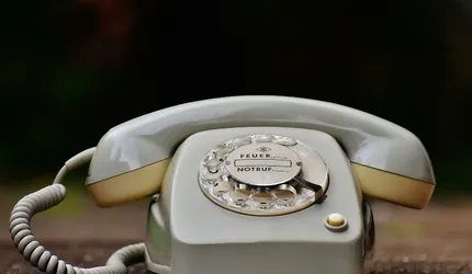 Close-up of a vintage rotary dial telephone with a nostalgic design on a wooden surface.
