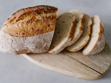 A rustic sourdough loaf with slices on a wooden