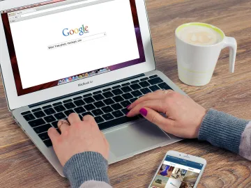 Hands typing on MacBook Air with Google search