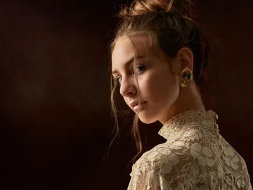 Portrait of a young woman with elegant hairstyle and lace dress, showcasing vintage earrings.