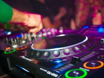 Close-up of a DJ's hands on mixing console at a vibrant party in Utrecht.