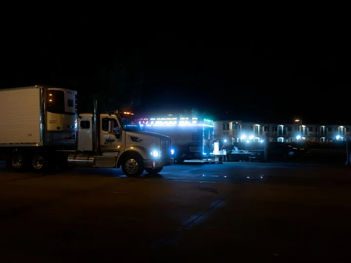 Two brightly lit trucks parked in an urban area at