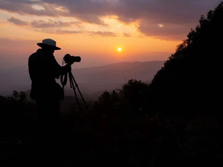 silhouette of a photographer who shoots a sunset in the moun