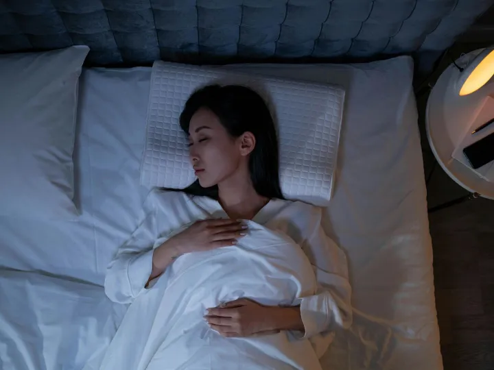 Calm and peaceful woman resting in bed under dim