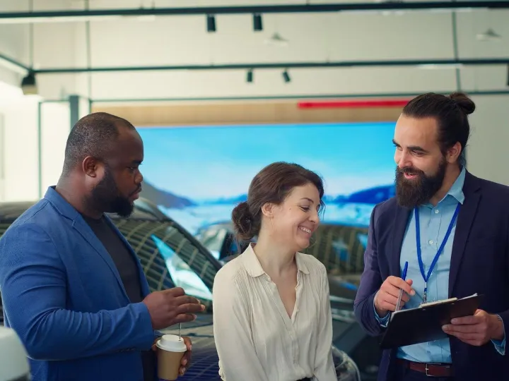 Car salesman gives sale contract for clients to sign after o