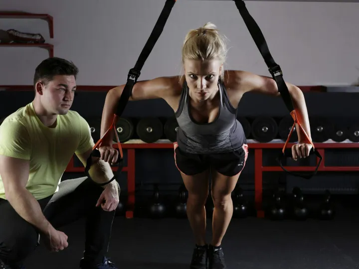 A woman performing strength training with a traine
