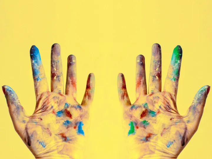 Colorful fingers spread against a bright yellow ba
