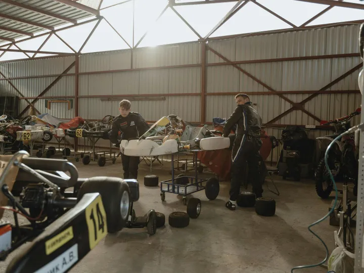 Two mechanics working on go-karts in an indoor wor