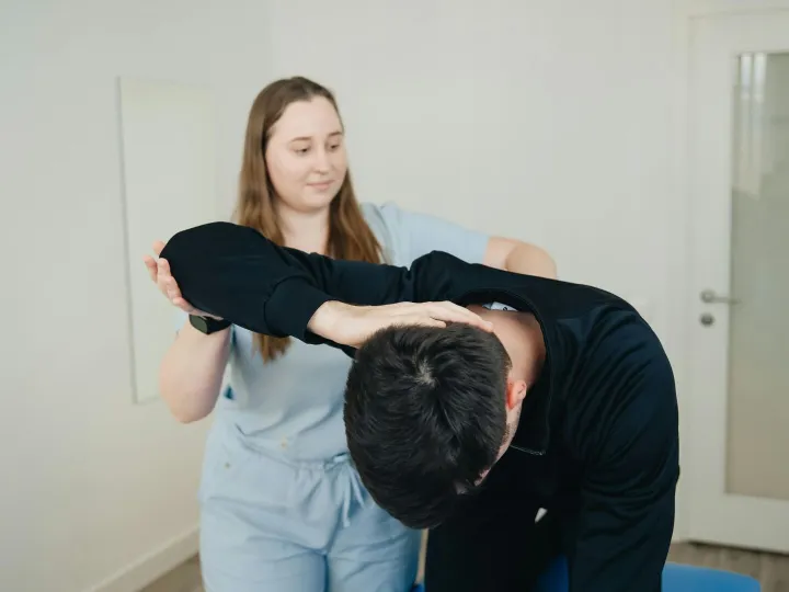A physiotherapist aids a patient in a stretching e